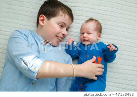 Big brother hugging his newborn baby girl. Toddler kid meeting new sibling Big brother hugging his newborn baby girl. Toddler kid meeting new sibling 47158458