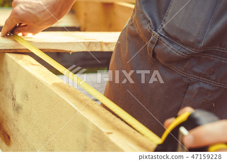 the worker makes measurements with a tape measure the worker makes measurements with a tape measure 47159228