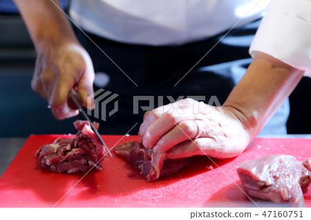 Butcher cut a piece of meat in kitchen 47160751