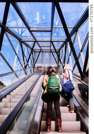 Woman with backpack up the escalator Woman with backpack up the escalator 47170794