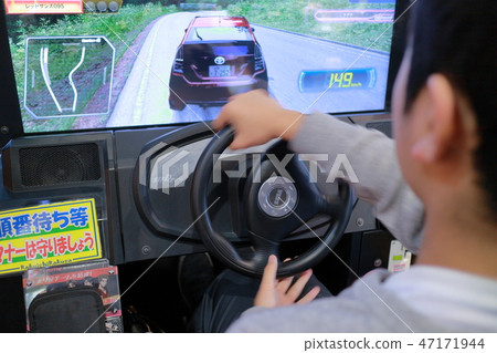 Boy enjoying car racing game in game center Boy enjoying car racing game in game center 47171944