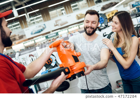 Salesman is giving new leaf blower to couple  47172284