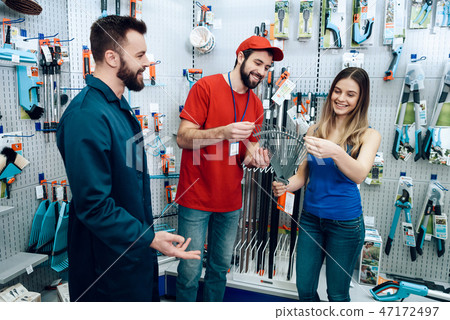 Two salesmen are showing female client new rake Two salesmen are showing female client new rake 47172497