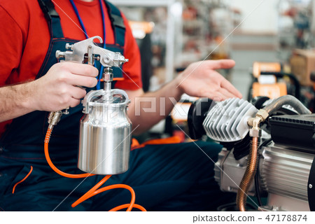Salesman is posing with compressor paint sprayer Salesman is posing with compressor paint sprayer 47178874