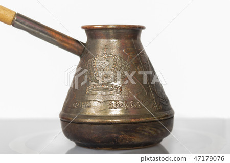 Closeup of rustic cezve on white stove against white wall, copy space Closeup of rustic cezve on white stove against white wall, copy space 47179076