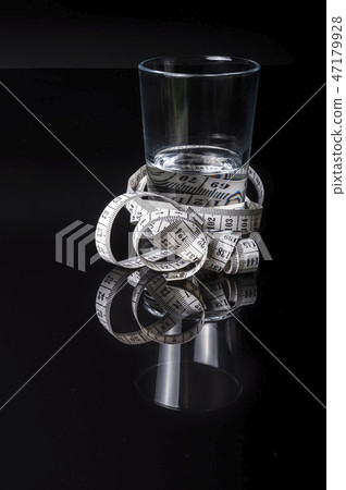 A water glass surrounded with measurement tape A water glass surrounded with measurement tape 47179928