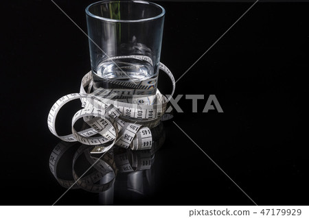 A water glass surrounded with measurement tape A water glass surrounded with measurement tape 47179929