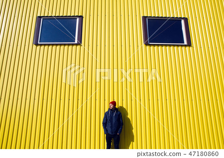 guy in the red hat stands at the wall of the iron house in nature guy in the red hat stands at the wall of the iron house in nature 47180860