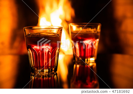 Glass of whiskey with ice near the fireplace 47181692