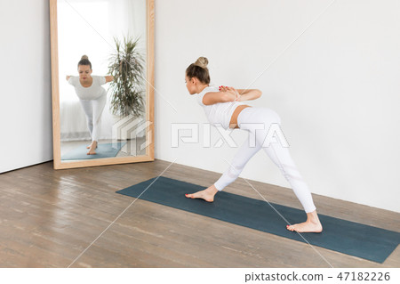 Sporty young woman doing yoga practice on white background at home. Sporty young woman doing yoga practice on white background at home. 47182226