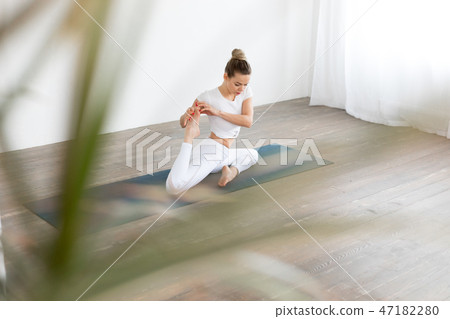 Sporty young woman doing yoga practice on white background at home. 47182280