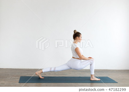 Sporty young woman doing yoga practice on white background at home. Sporty young woman doing yoga practice on white background at home. 47182299