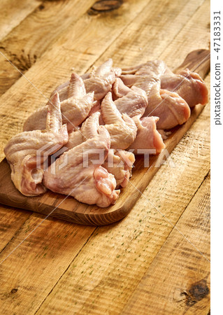Fresh raw organic chicken wings on chopping board on wooden table. 47183331