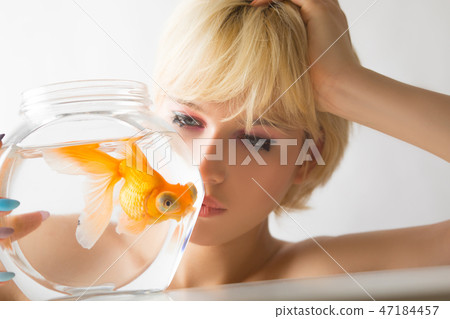Portrait of a beautiful girl with a goldfish in an aquarium. 47184457