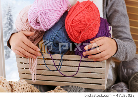 Child girl sitting on window sill with wool yarns Child girl sitting on window sill with wool yarns 47185022