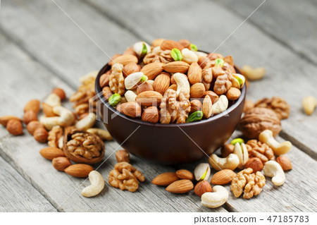 Wooden bowl with mixed nuts on a wooden gray background. Walnut, pistachios, almonds, hazelnuts and Wooden bowl with mixed nuts on a wooden gray background. Walnut, pistachios, almonds, hazelnuts and 47185783