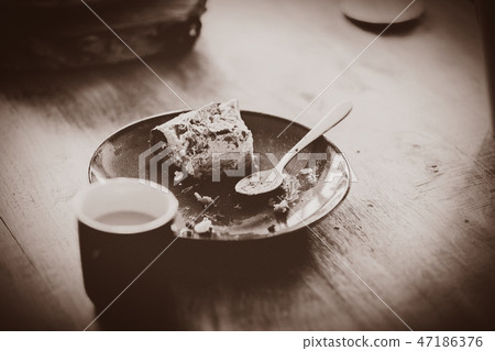 Plate with eaten cake and spoon on wooden table 47186376
