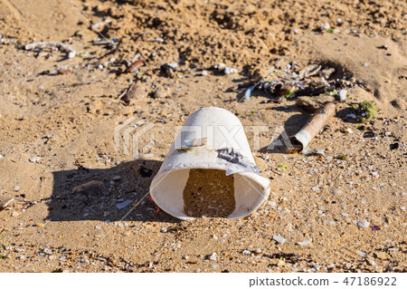Disposable tableware glass on sandy beach after tide Disposable tableware glass on sandy beach after tide 47186922