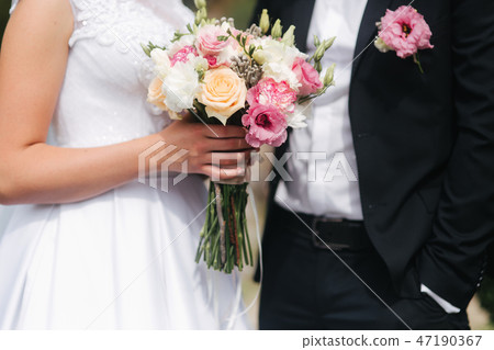Wedding bouquet in brides hands. Close up view of couples hands holding wedding bouquet. Flowers 47190367