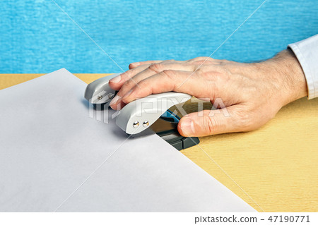 Hole punch makes holes in blank sheet of paper. Hole punch makes holes in blank sheet of paper. 47190771