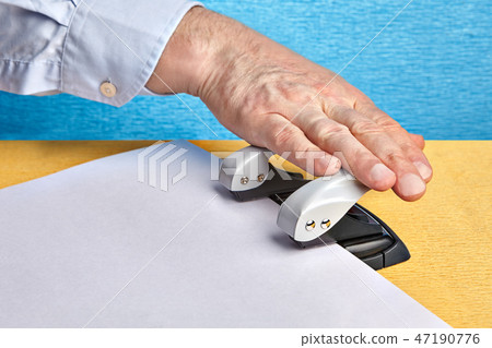 Hand makes holes in paper with punch hole. Hand makes holes in paper with punch hole. 47190776