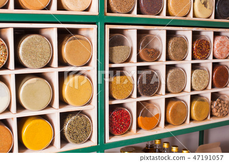 Collection of glass jars with spices on wooden stand 47191057
