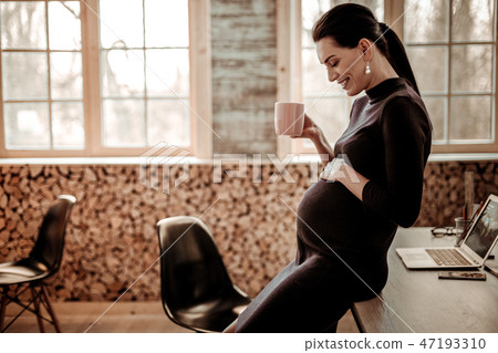 Positive pregnant woman looking at her belly Positive pregnant woman looking at her belly 47193310