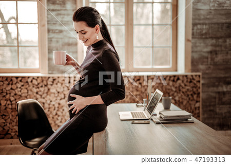 Delighted pregnant woman having a cup of tea Delighted pregnant woman having a cup of tea 47193313