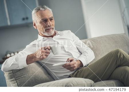 Man wearing white shirt drinking tea in the evening 47194179