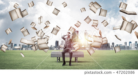Many old books falling from above and student guy sitting on ben 47202086