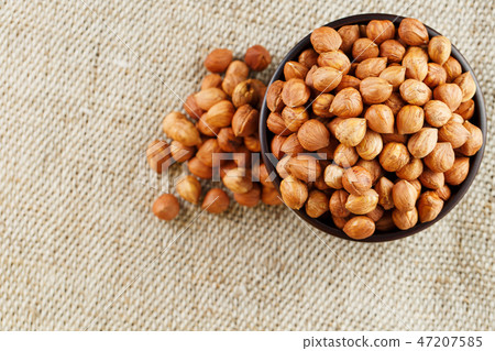 Peeled hazelnuts in a wooden, dark brown cup on Peeled hazelnuts in a wooden, dark brown cup on 47207585