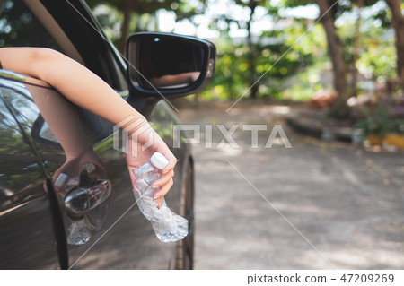 Hand throwing plastic bottle on the road 47209269