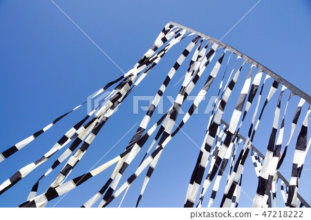 Red, black and white kite flying in the blue sky. Red, black and white kite flying in the blue sky. 47218222