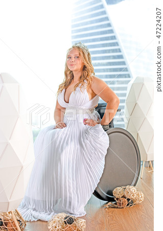 Beautiful disabled bride posing in a wheelchair against the background of a panoramic window 47224207