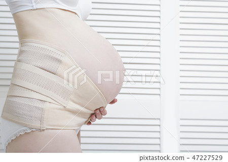 Woman puts on a bandage for pregnant women Woman puts on a bandage for pregnant women 47227529