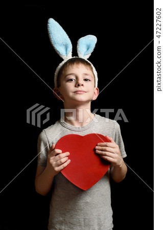 Blond boy in hare ears holds heart shape red box Blond boy in hare ears holds heart shape red box 47227602