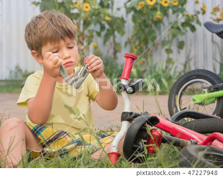 Boy fixing bicycle. Front, back yard background. Transport and children. Cycle on the grass. Happy Boy fixing bicycle. Front, back yard background. Transport and children. Cycle on the grass. Happy 47227948
