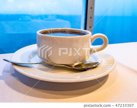 Cup of coffee on a table whith the ocean in background while the cruise vessel is driving Cup of coffee on a table whith the ocean in background while the cruise vessel is driving 47233307