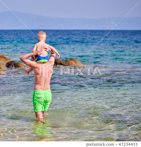 Toddler boy on father's shoulders at beach 47234433