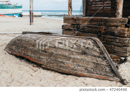 Old rusty wooden fishing boat laying overturned Old rusty wooden fishing boat laying overturned 47240498