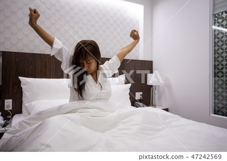 asian young woman stretching on bed after waking asian young woman stretching on bed after waking 47242569