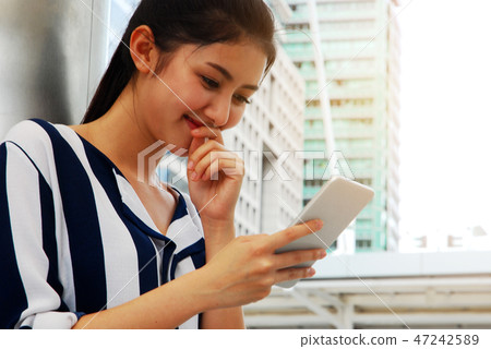 Beautiful woman smile portrait and playing mobile Beautiful woman smile portrait and playing mobile 47242589