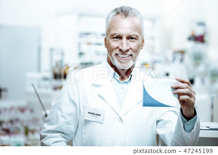 Pleased mature pharmacist demonstrating box with tablets Pleased mature pharmacist demonstrating box with tablets 47245199