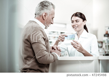 Pleasant cheerful dark-haired pharmacist talking to her grey-haired client 47245498