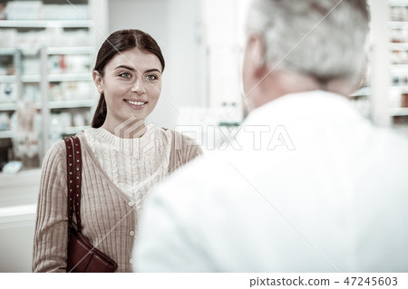 Beaming pleasant client of drugstore talking to professional pharmacist 47245603