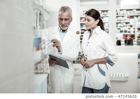 Bearded owner of drugstore giving some instructions while hiring new pharmacist Bearded owner of drugstore giving some instructions while hiring new pharmacist 47245628