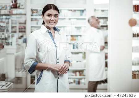Green-eyed pharmacist. Appealing green-eyed pharmacist smiling broadly while meeting clients in Green-eyed pharmacist. Appealing green-eyed pharmacist smiling broadly while meeting clients in 47245629