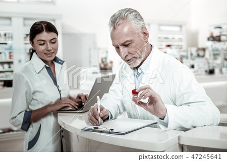 Two professional pharmacists making checkup of medicine range in their drugstore 47245641