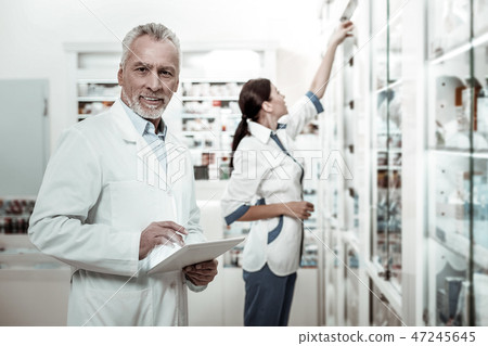 Mature prosperous director of drugstore holding tablet while making order Mature prosperous director of drugstore holding tablet while making order 47245645