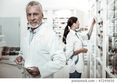 Bearded mature first-line pharmacist feeling joyful while working hard Bearded mature first-line pharmacist feeling joyful while working hard 47245650